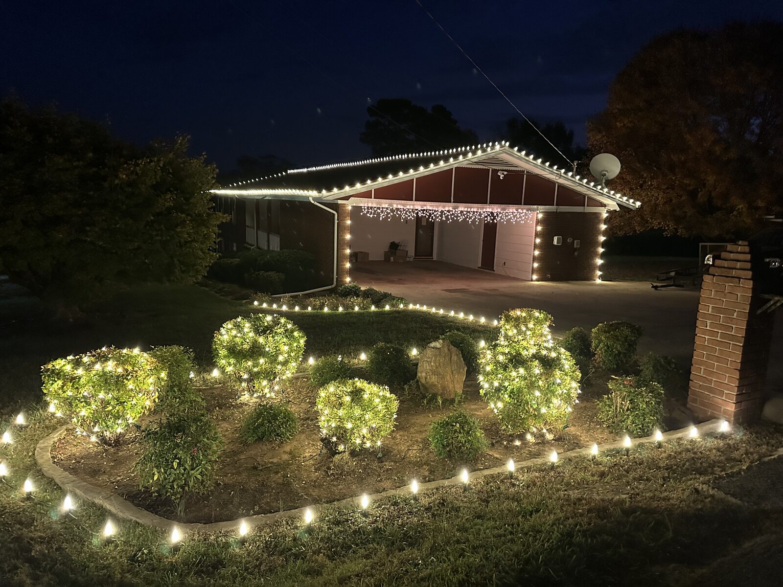 Brick home with holiday lighting along the roof and windows