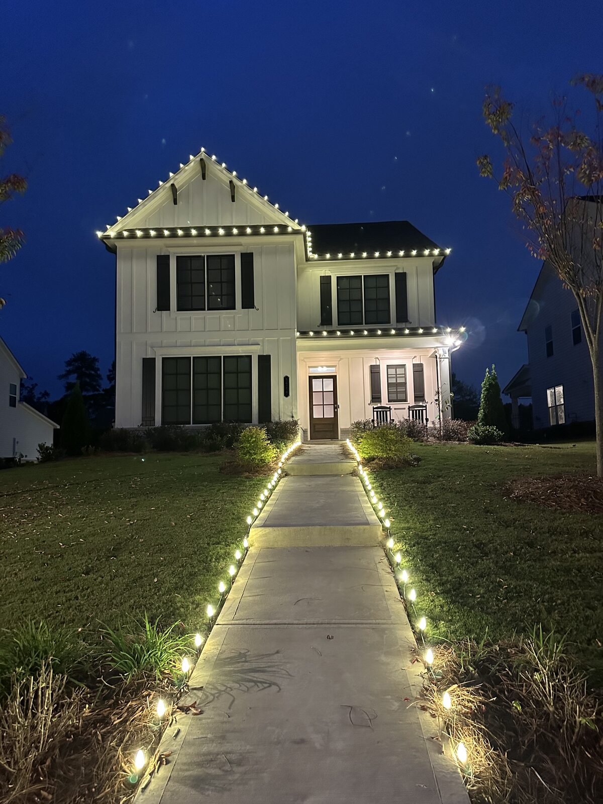 Front entry framed with lighted garland and a wreath